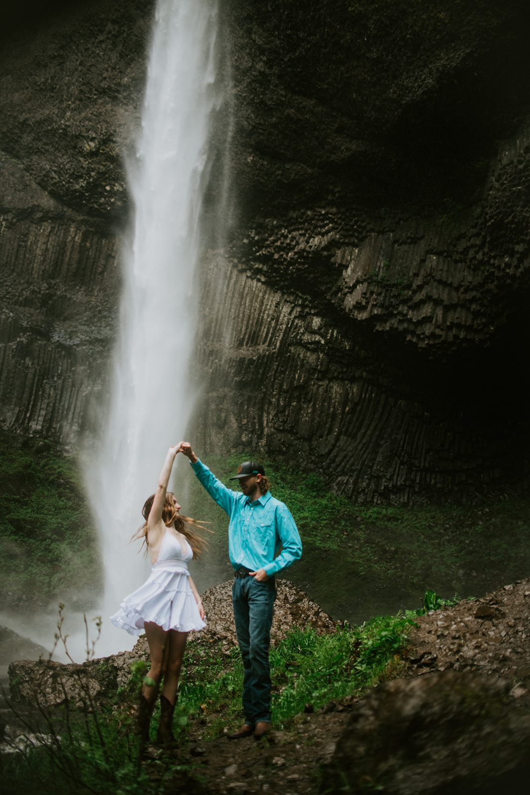 Couple twirling in front of waterfall, playful and candid outdoor engagement photos in Oregon