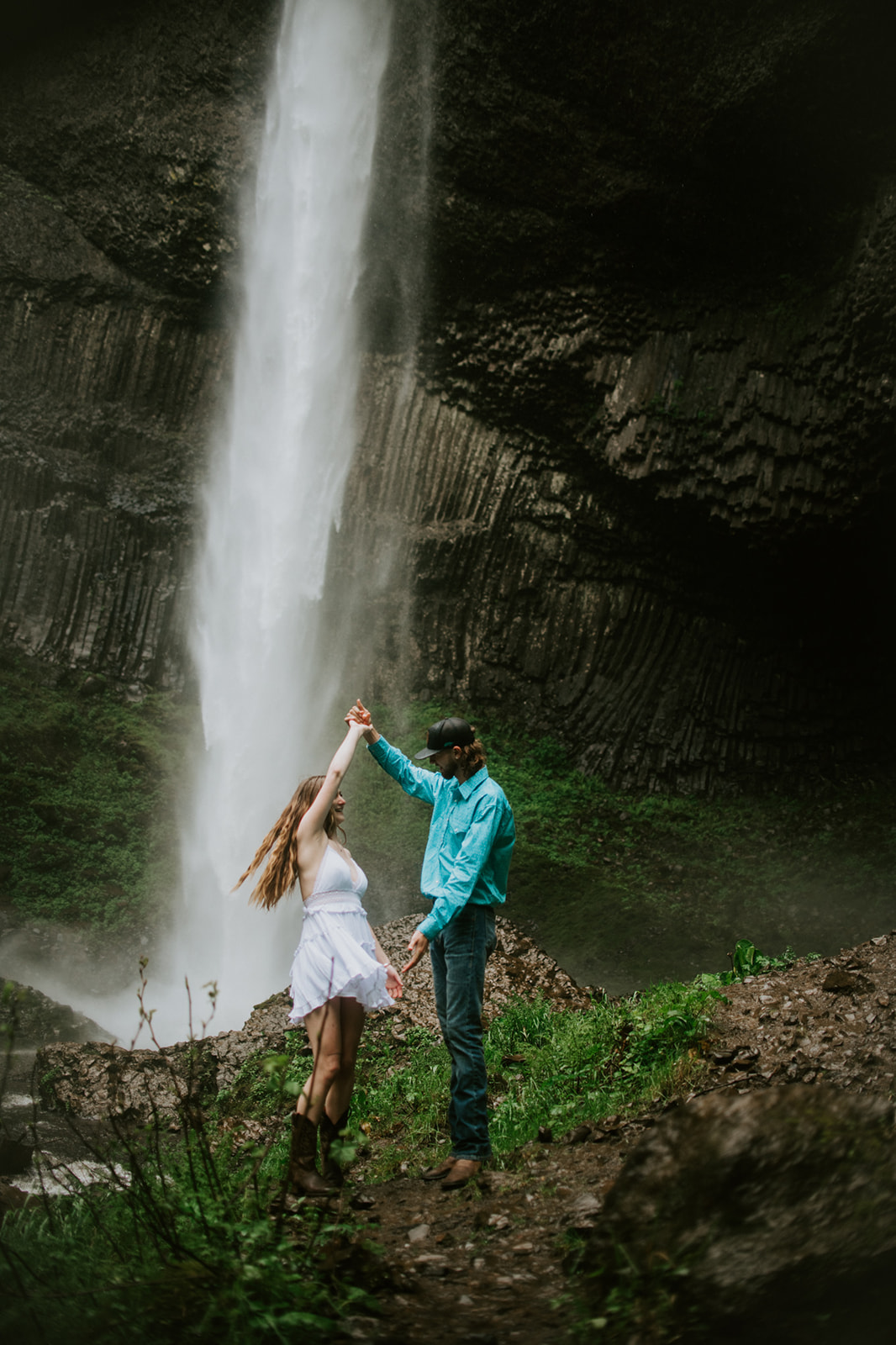 Couple twirling and dancing in front of a waterfall during outdoor engagement photos in Oregon