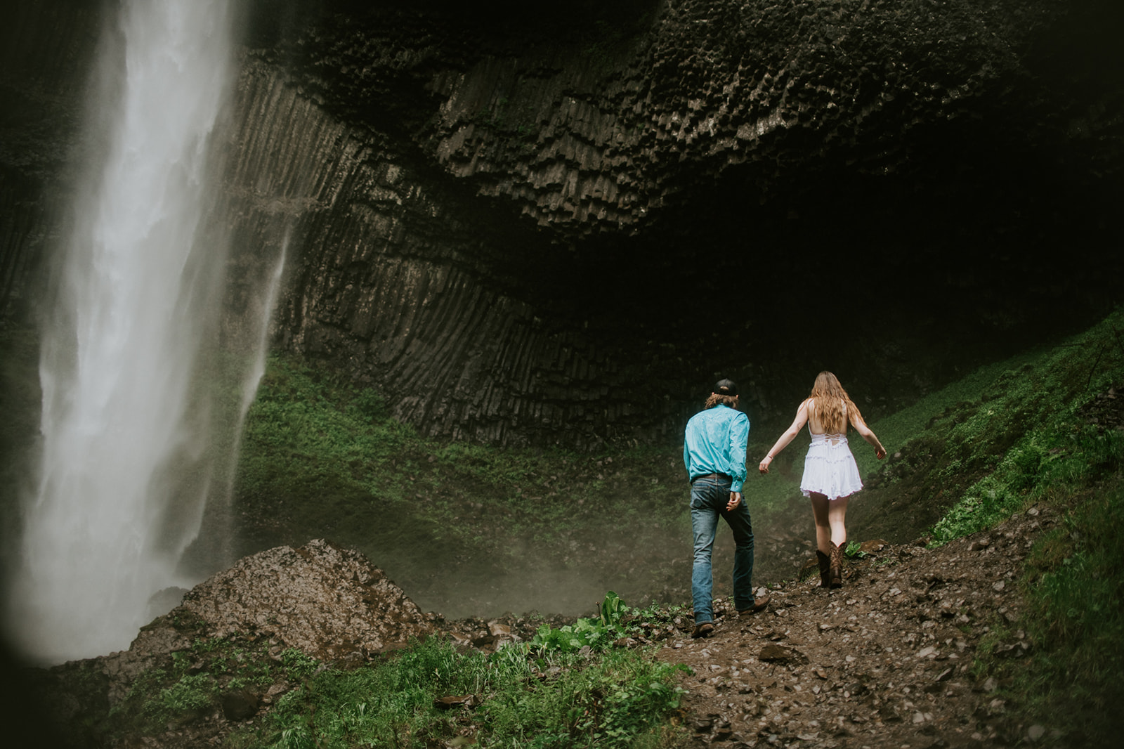 Couple walking together along waterfall trail, wide landscape engagement photo in Oregon