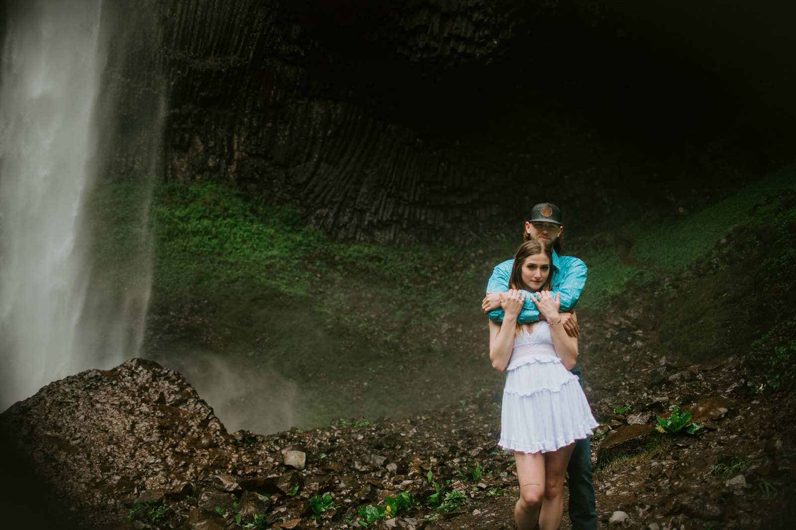 Couple embracing with waterfall in background, romantic and natural engagement moment