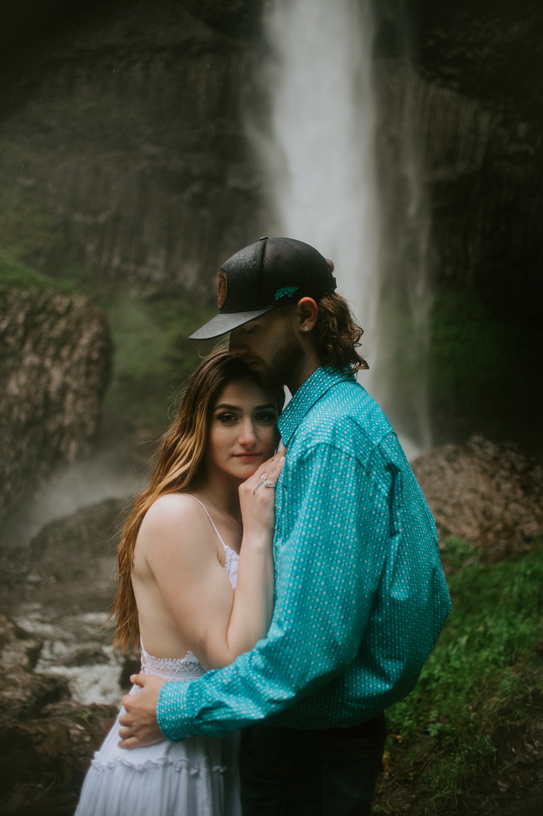 Couple embracing with waterfall behind them, soft mist and natural movement captured