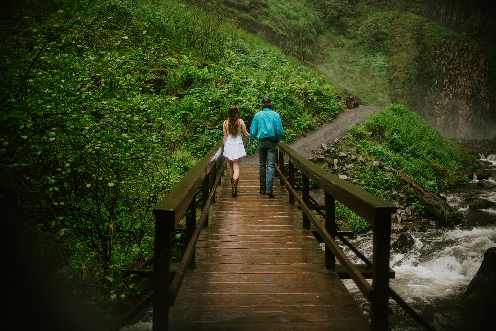 Couple walking away together across wooden bridge in forest, quiet and connected moment