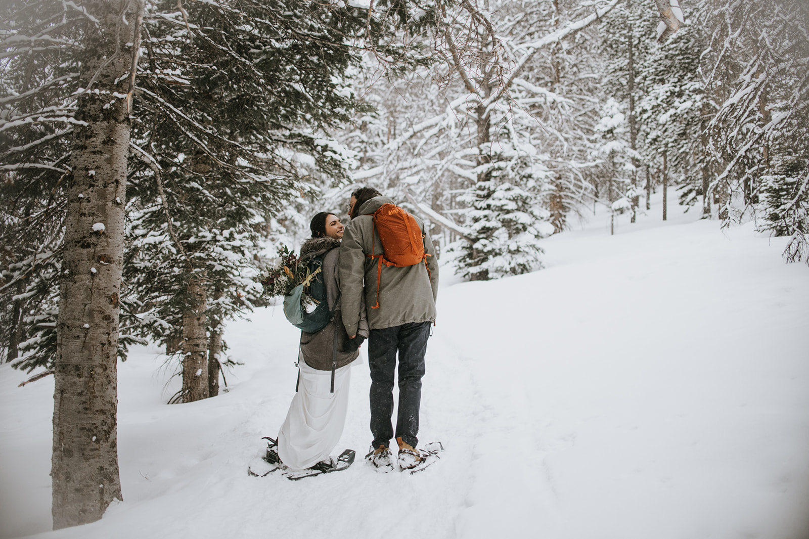 Quiet engagement photoshoot moment with couple pausing together in a snowy forest clearing