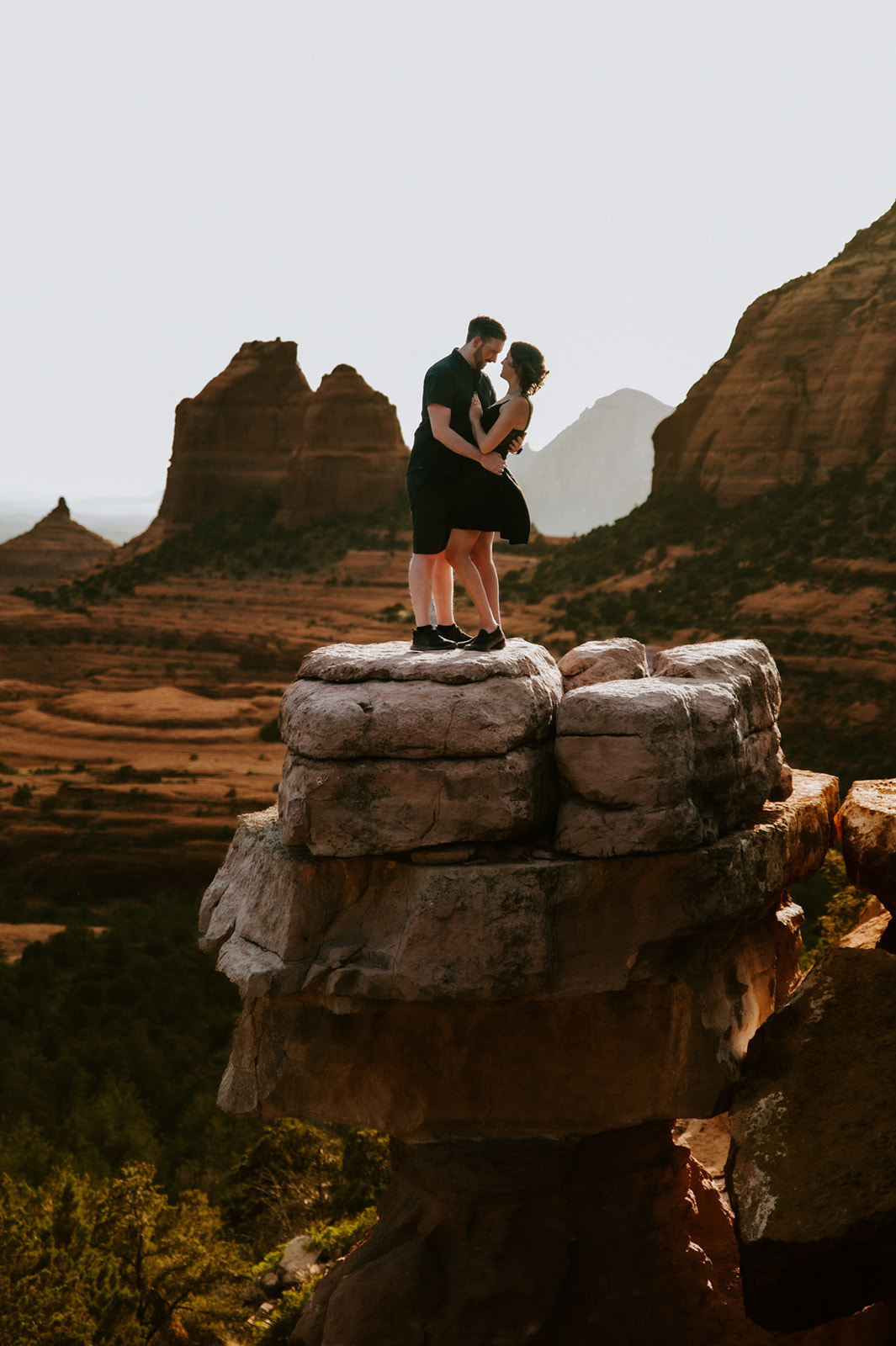 Adventurous couple standing on a rock formation after choosing to elope to Sedona, surrounded by dramatic desert views