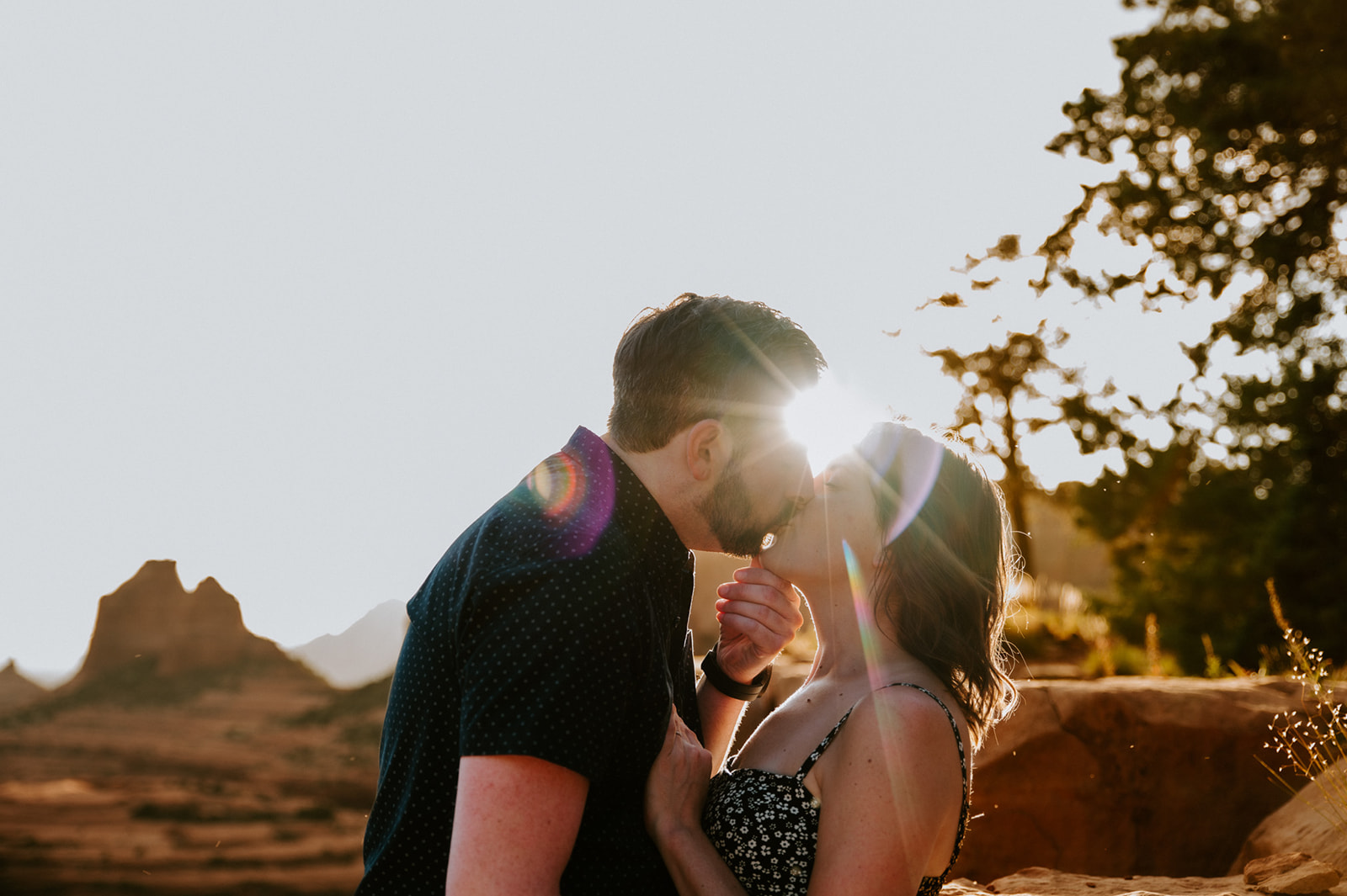 Intimate sunlit kiss with lens flare during a couple’s decision to elope to Sedona