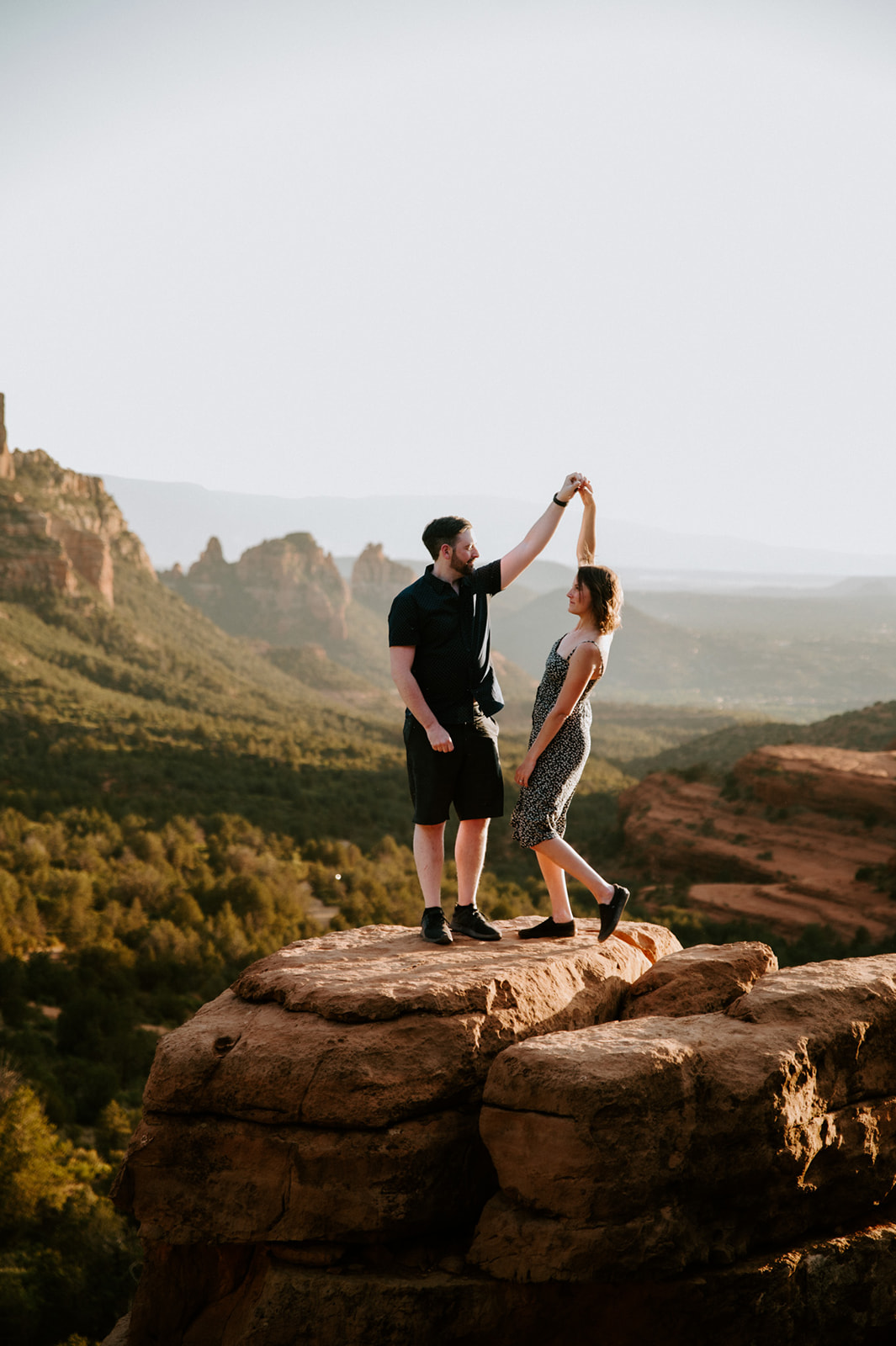 Couple dancing together on a rock ledge at golden hour after they elope to Sedona
