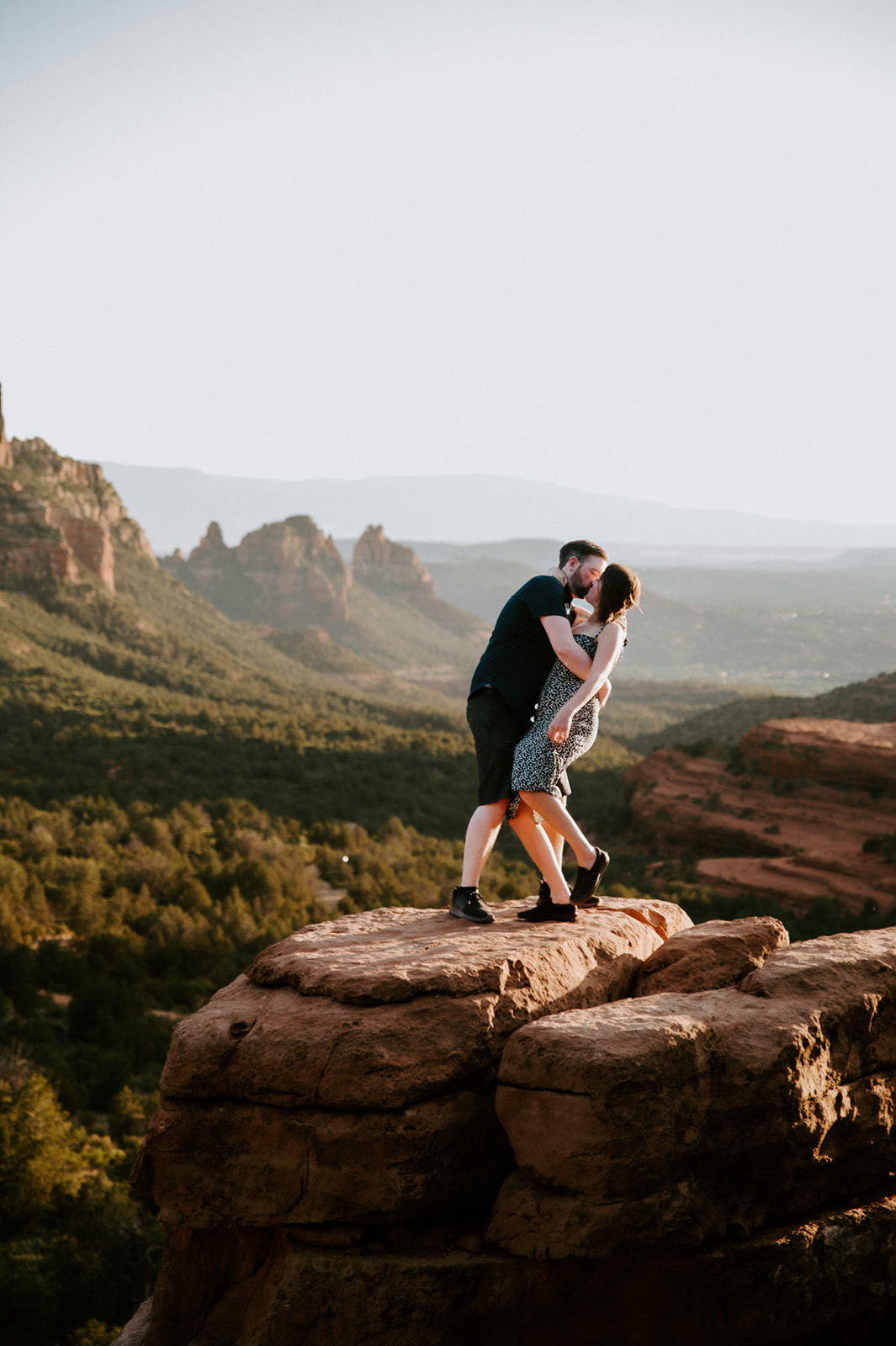 Couple embracing on a rock ledge at golden hour after choosing to elope to Sedona