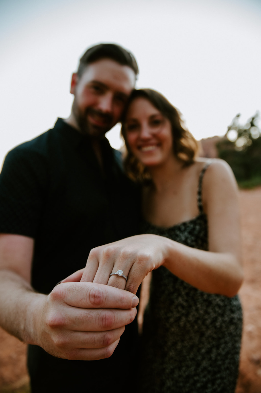Playful close-up of a couple showing off an engagement ring during their Sedona proposal moment