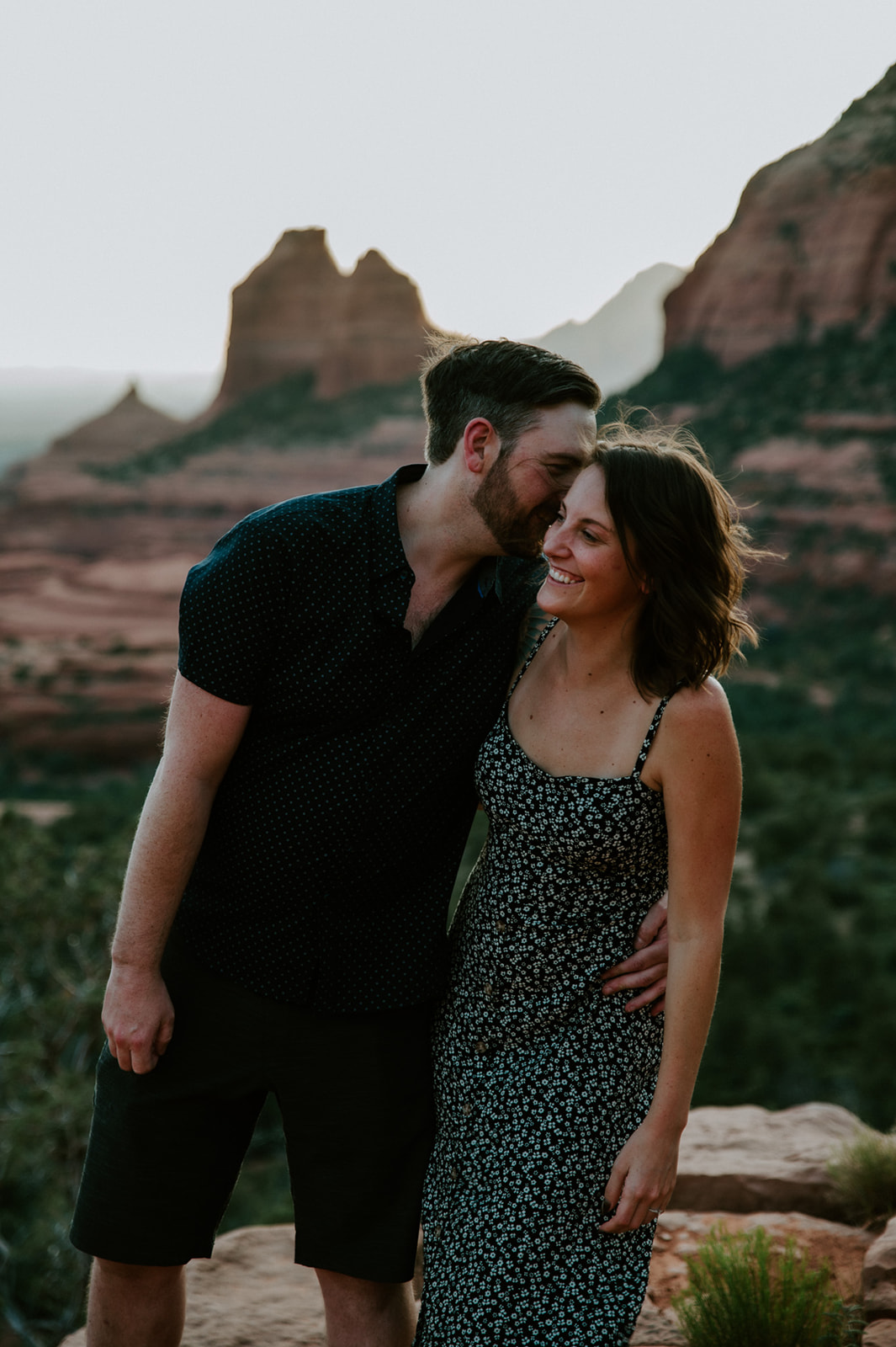 Couple sharing a quiet, close moment with Sedona’s mountains softly blurred behind them