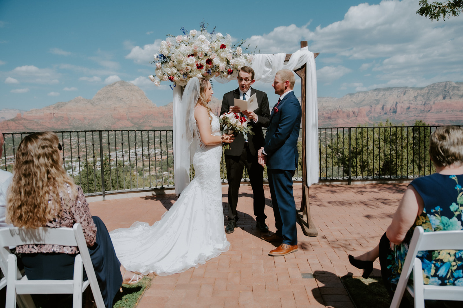 Outdoor ceremony setup with a floral arch and guests gathered as a couple elopes in Sedona