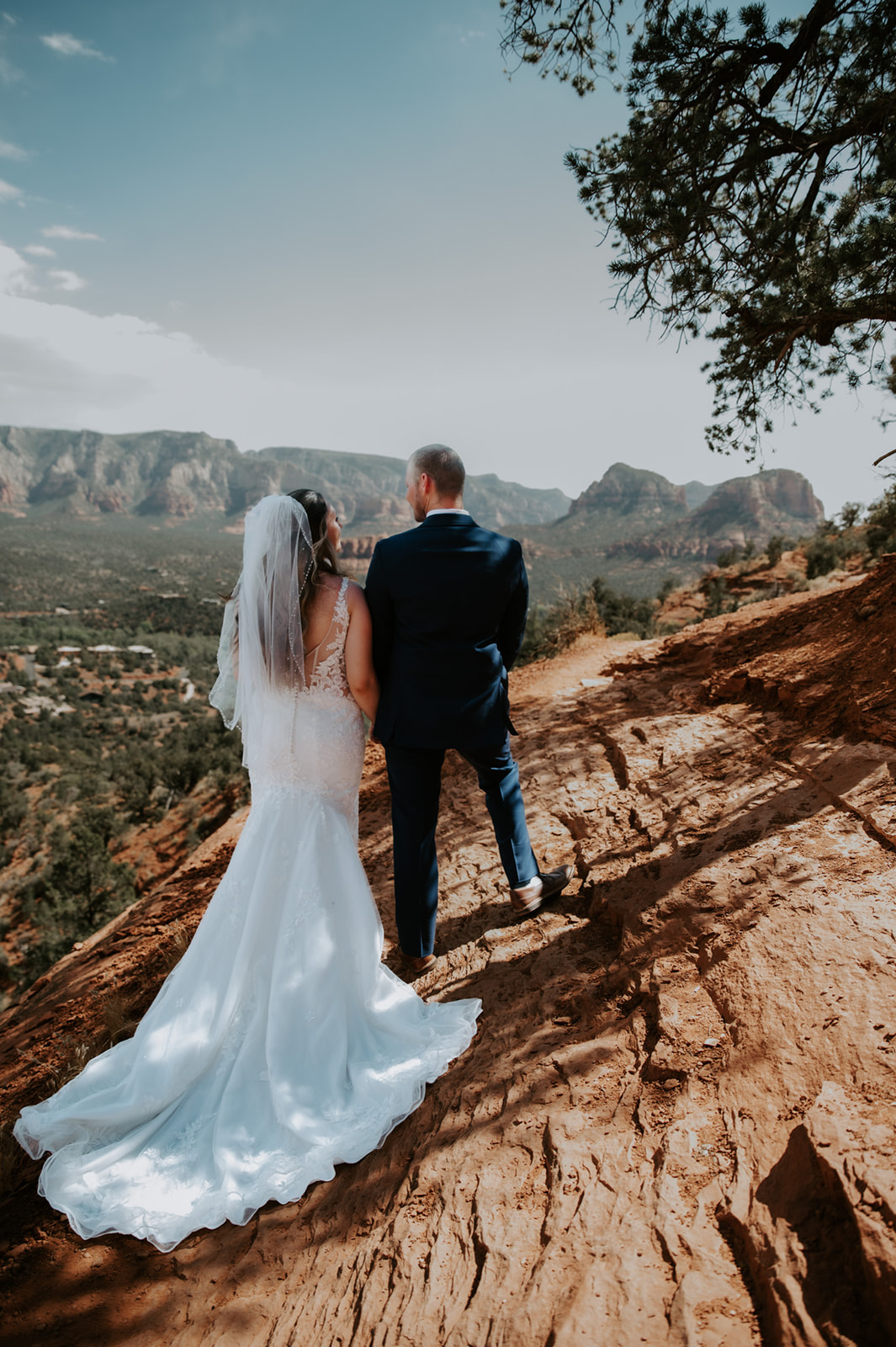 Bride and groom standing on a red rock overlook, taking in the view after they elope to Sedona