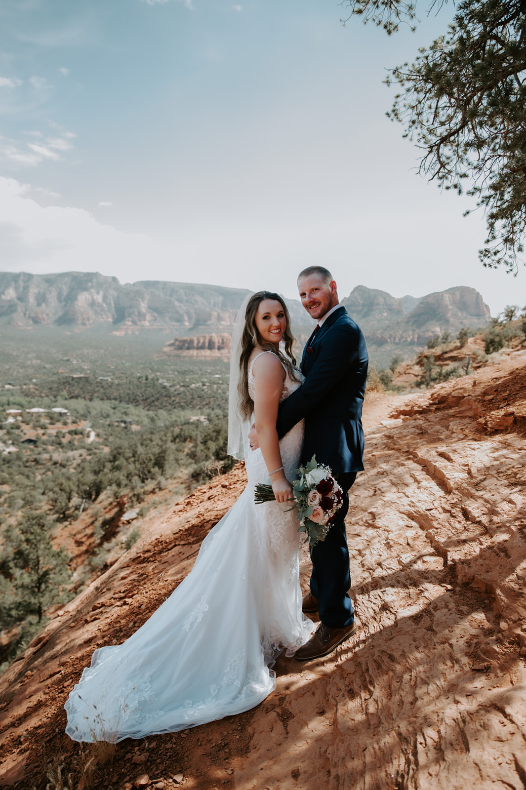 Bride and groom smiling together on a red rock overlook during their Sedona elopement day