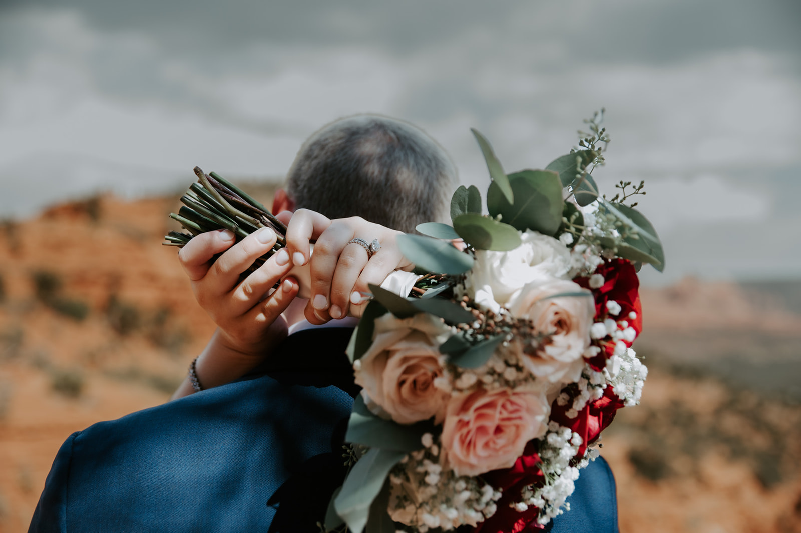 Close-up of a bride wrapping her arms around her partner while holding a bouquet during their Sedona elopement