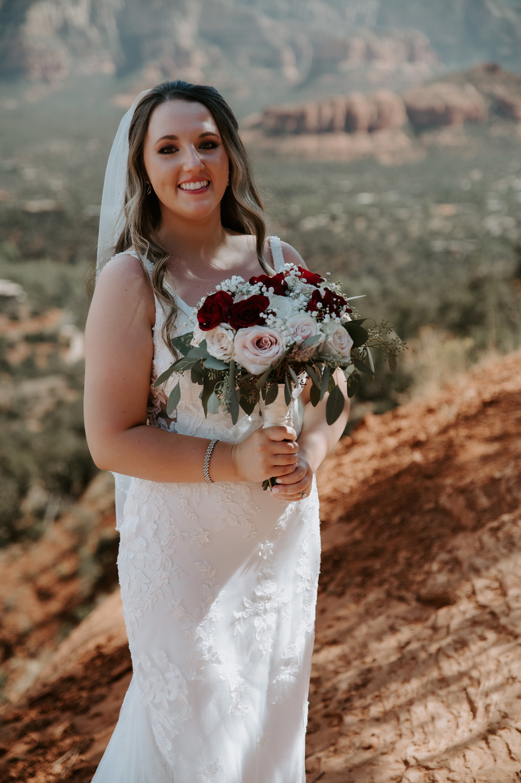 Bride holding her bouquet and smiling during her outdoor ceremony after choosing to elope to Sedona