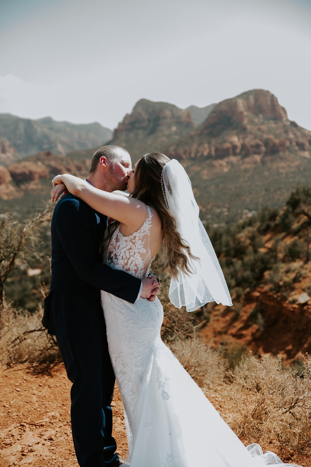 Bride and groom sharing a kiss with mountains in the background after they elope to Sedona