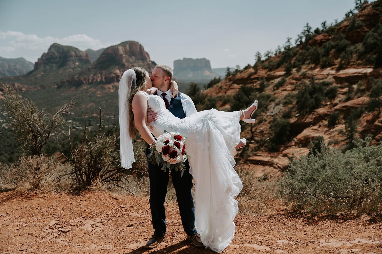 Groom lifting the bride during a joyful moment after they elope to Sedona in the desert landscape