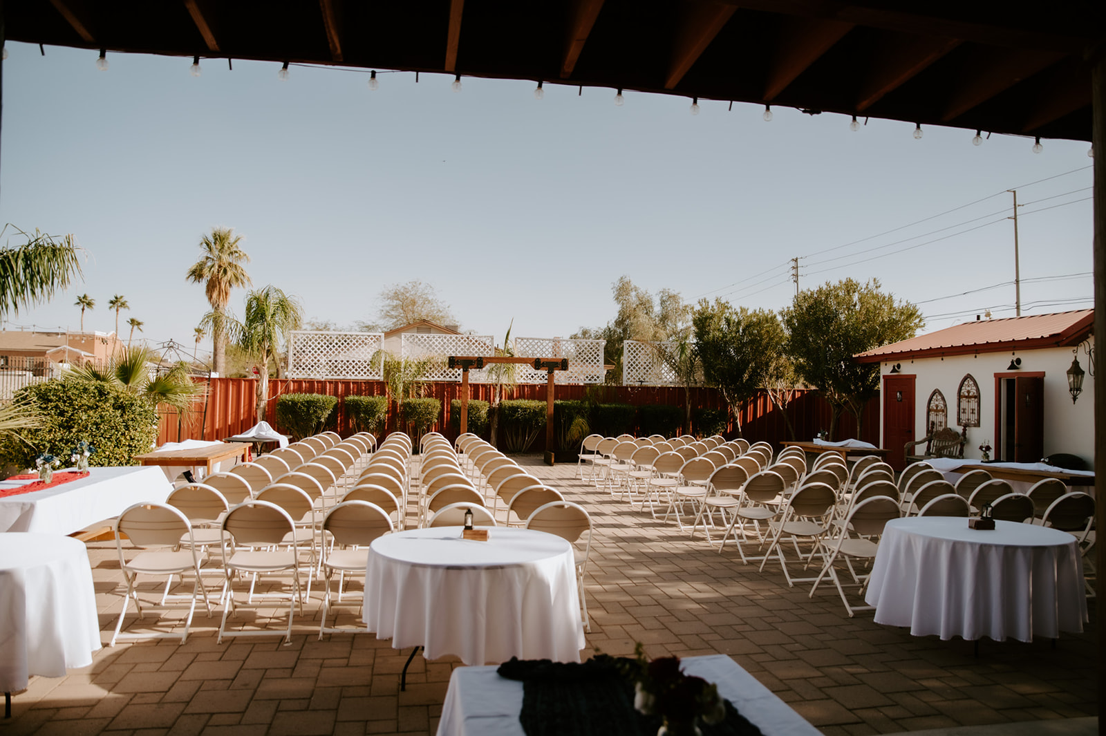 Outdoor wedding ceremony setup with white chairs and modern wooden altar before guests arrive