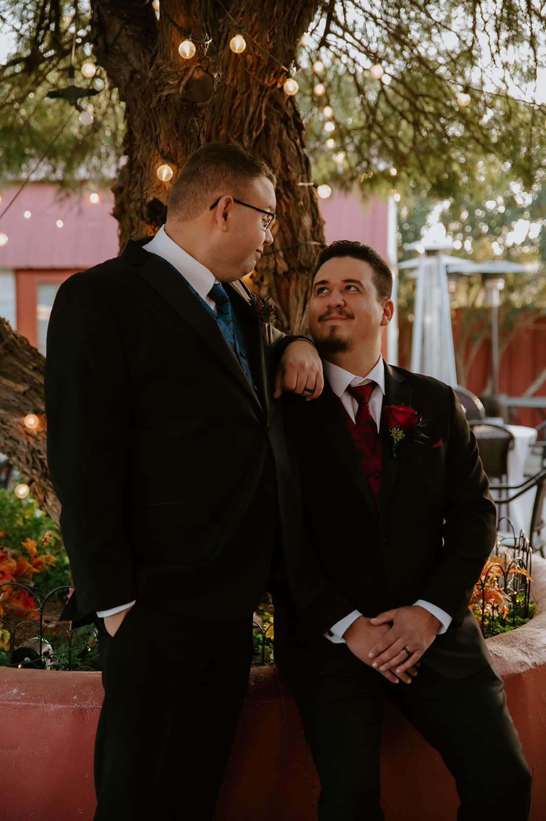 Romantic portrait of two grooms laughing together beneath café lights during an intimate wedding photographed by an LGBTQ wedding photographer