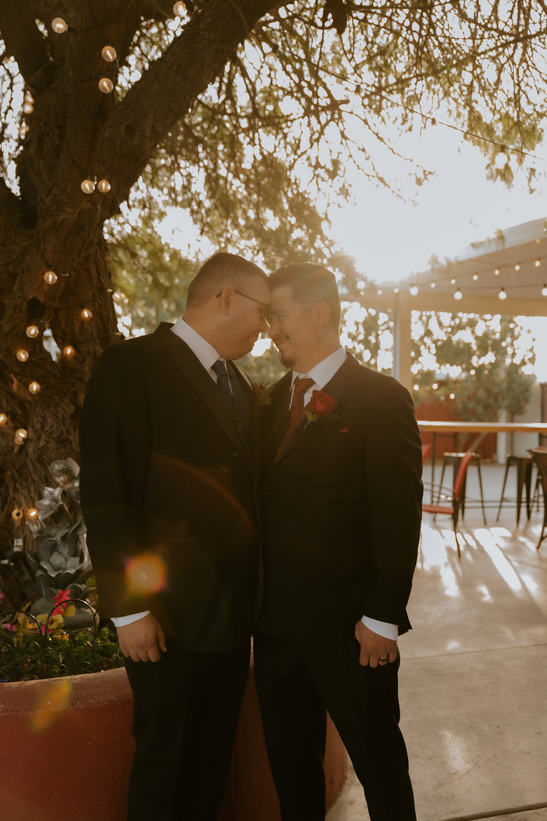 Groom and groom sharing a quiet golden hour moment under string lights during an intimate wedding day photographed by an LGBTQ wedding photographer