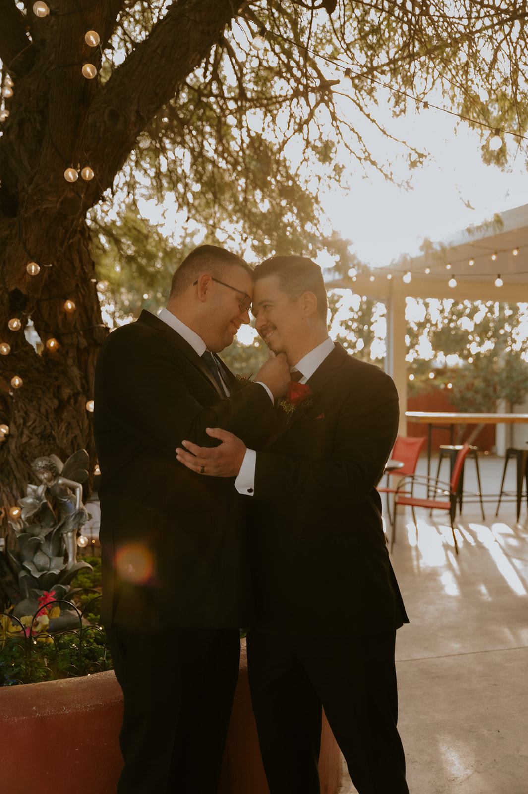 Romantic same-sex wedding portraits beneath glowing string lights captured by an LGBTQ wedding photographer