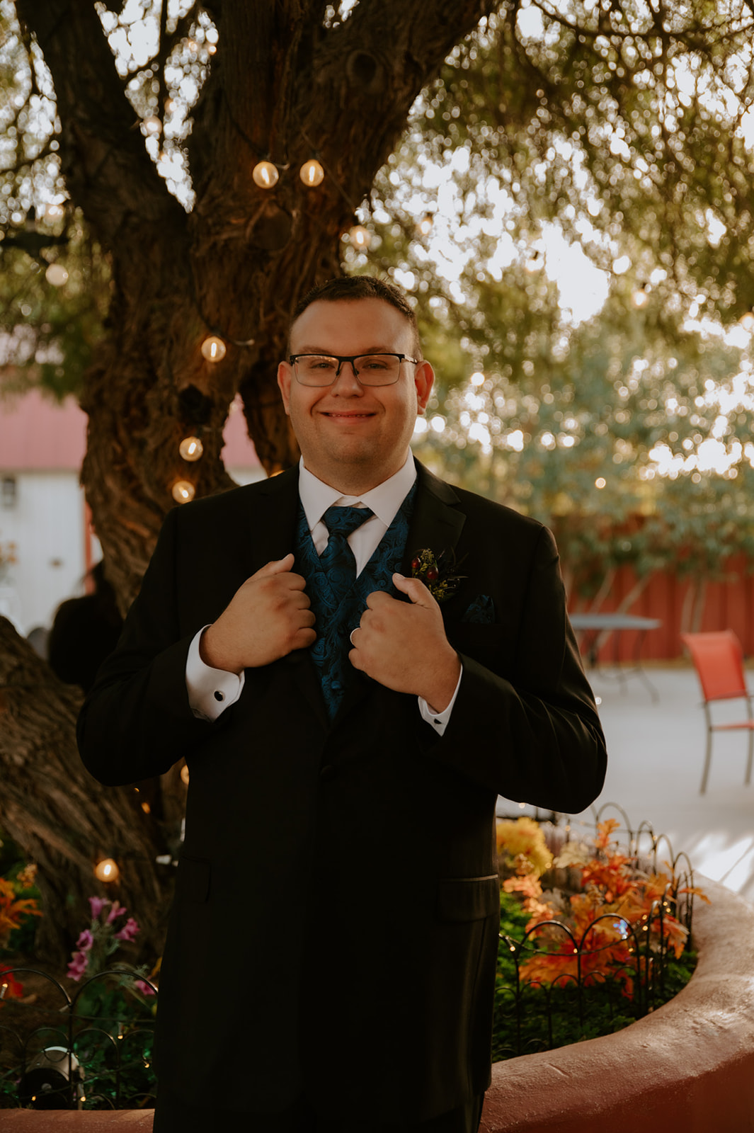 Groom portrait beneath glowing string lights before an emotional outdoor wedding ceremony