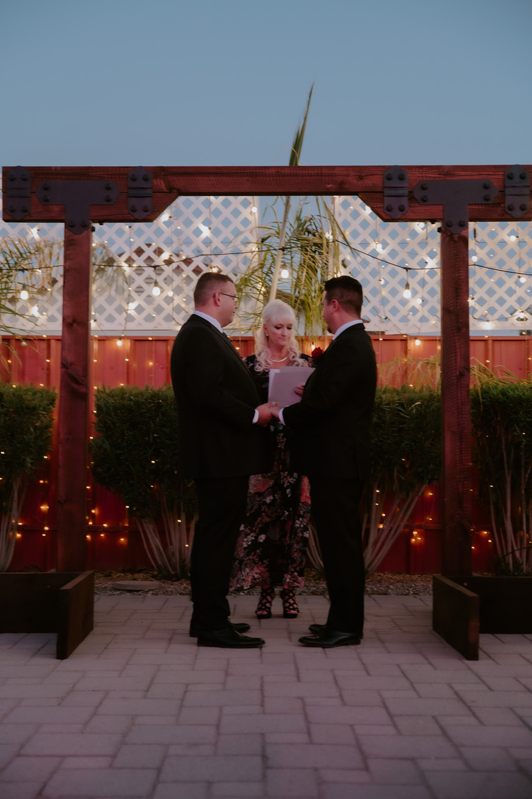 Intimate wedding ceremony for two grooms during an outdoor LGBTQ wedding celebration at sunset