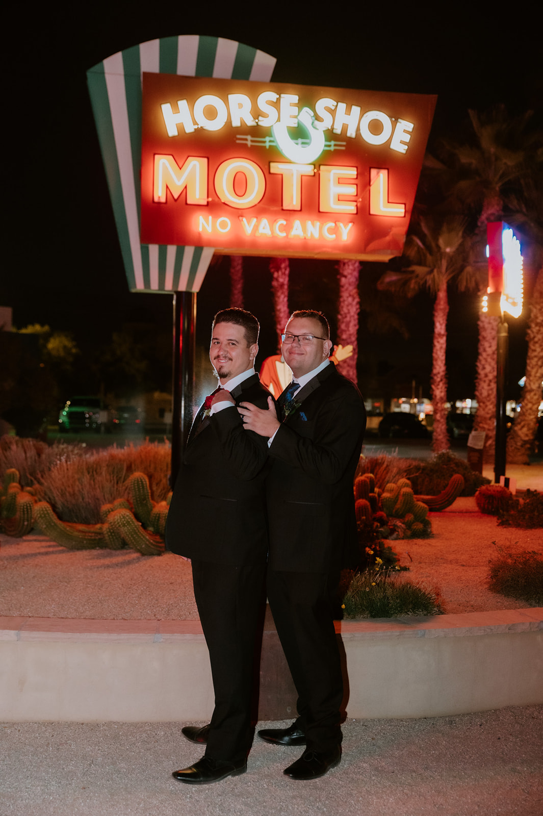 Groom and groom posing together outside the Horseshoe Motel during a retro-inspired nighttime wedding portrait session