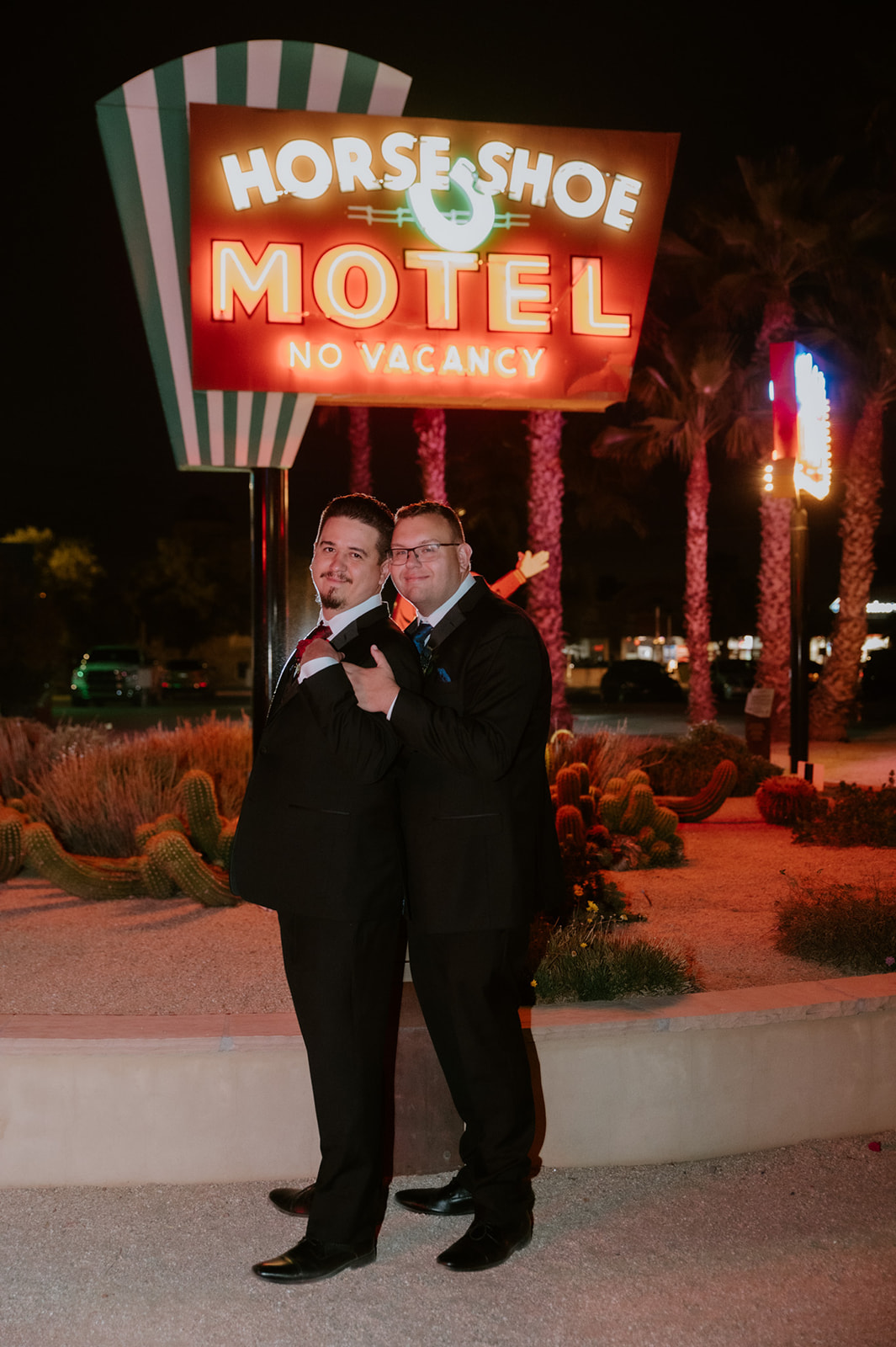 Same-sex couple posing outside the Horseshoe Motel during a retro-inspired wedding night photographed by an LGBTQ wedding photographer