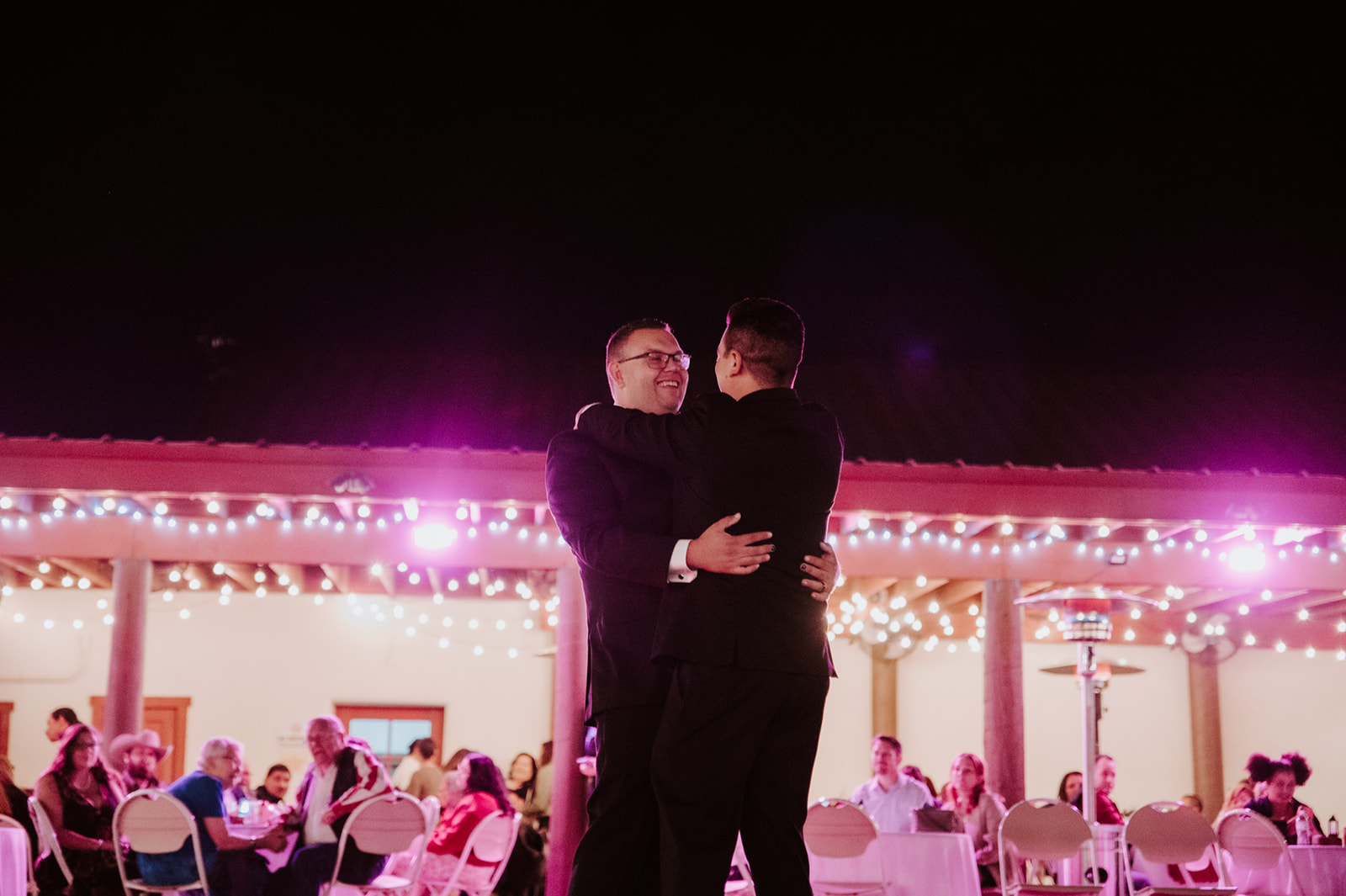 Same-sex couple sharing their first dance during a colorful wedding reception with emotional candid photography