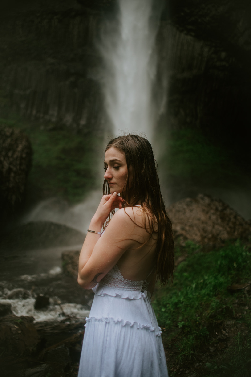 Moody portrait of bride standing beside a waterfall during an adventurous eloping in Oregon session.