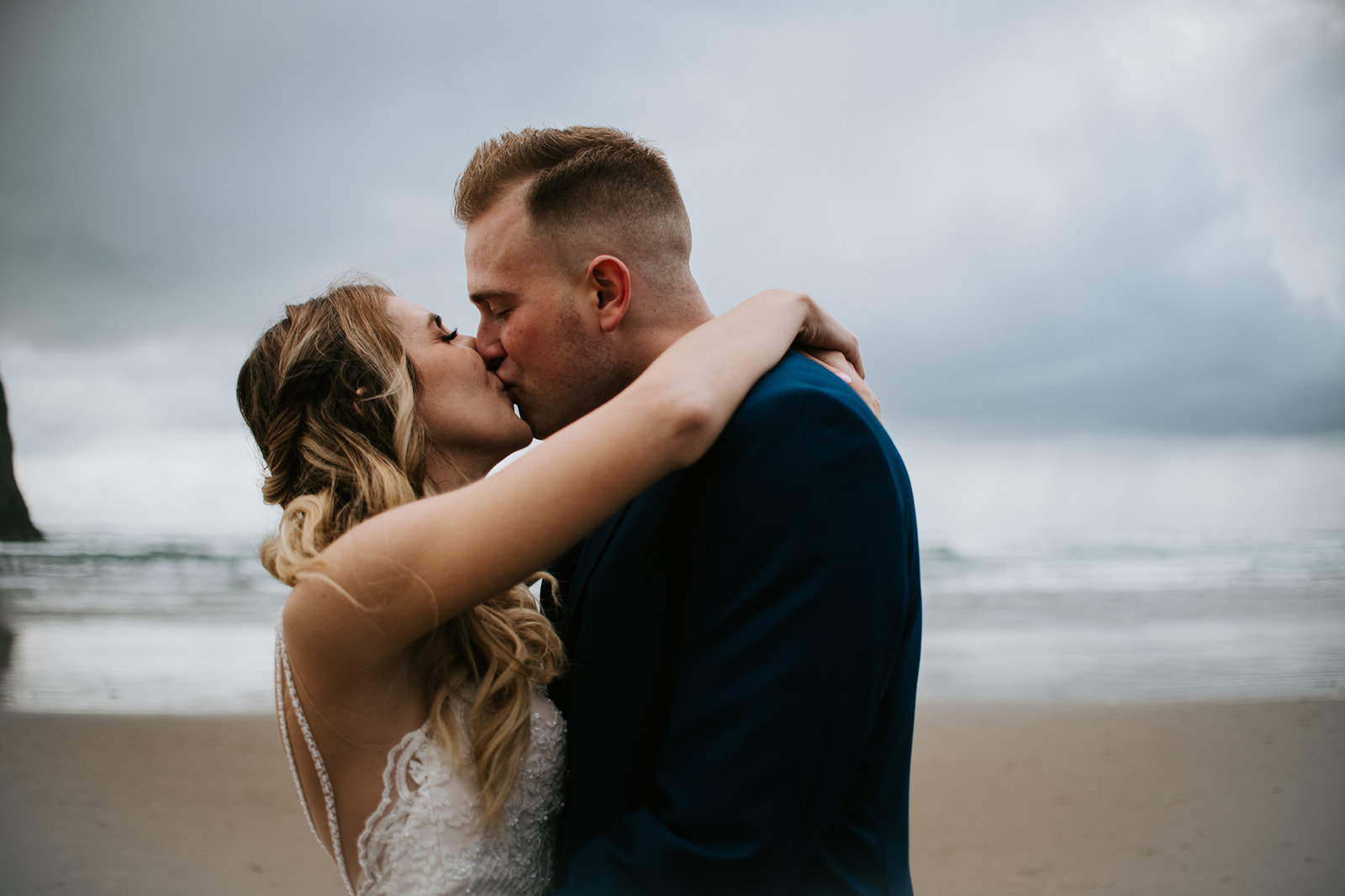 Close-up beach portrait of couple kissing during a windy day eloping in Oregon on the coast.
