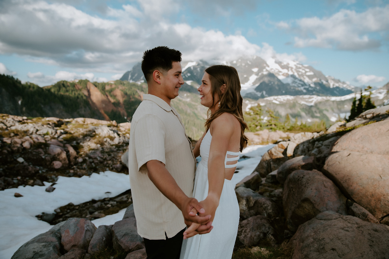 Couple holding hands during a North Cascades elopement with snowy mountain views behind them
