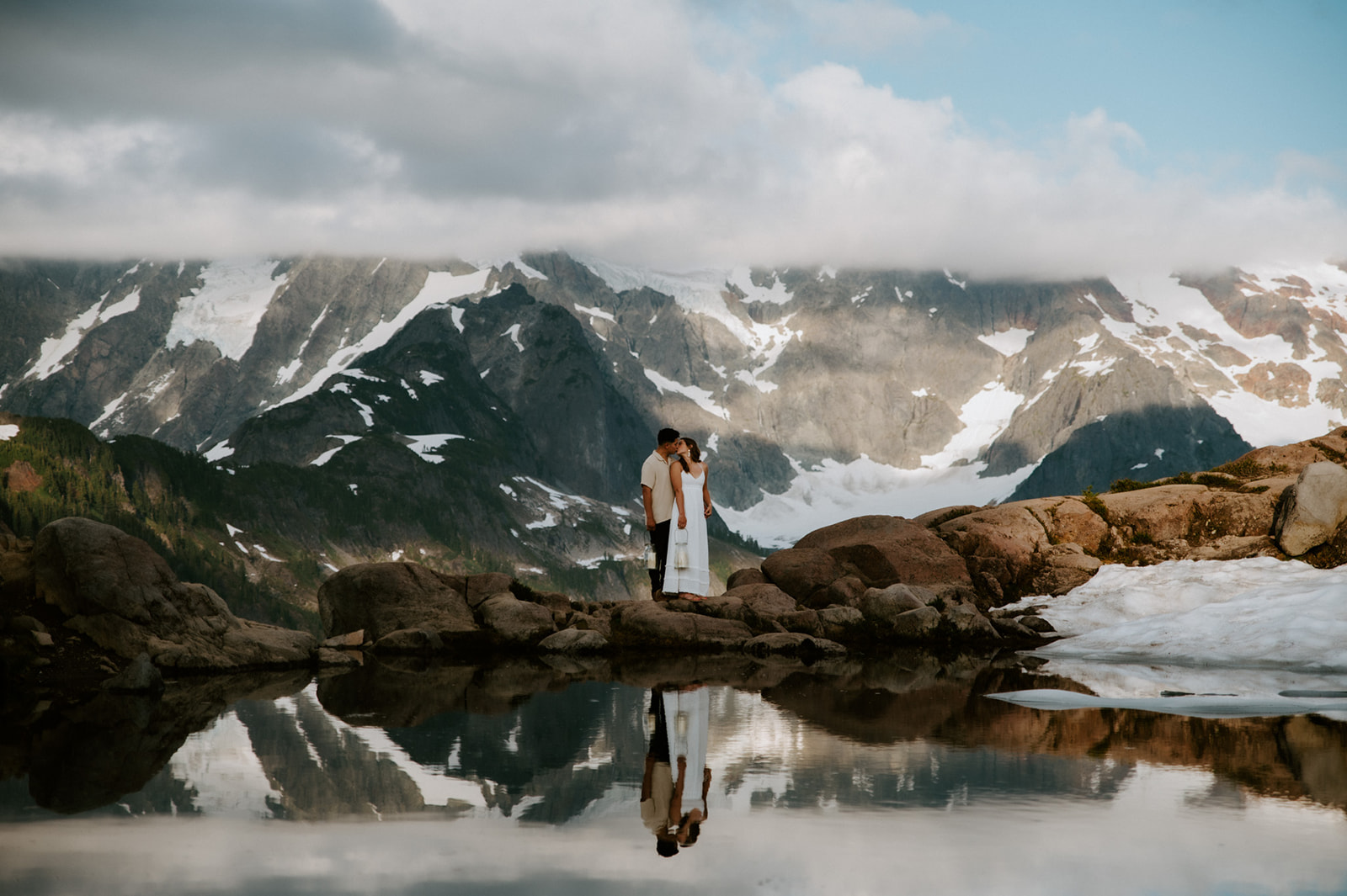 Couple standing beside reflective alpine lake during a North Cascades elopement with glacier mountain views
