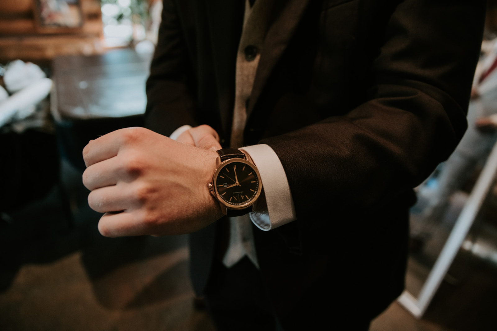 Groom adjusts his watch while getting ready, showcasing classic wedding day style and details.
