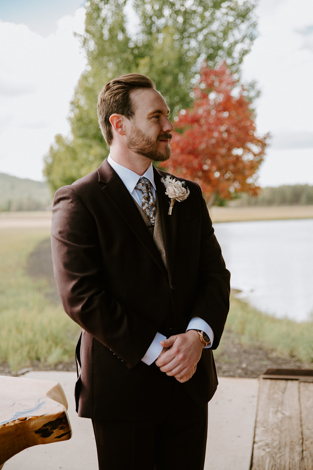 Groom waits at the altar overlooking a lake and forest, creating inspiration for couples planning an elopement in nature.
