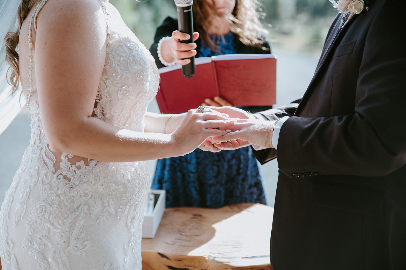 Close-up of the wedding ring exchange during the ceremony as the officiant reads from a ceremony book.
