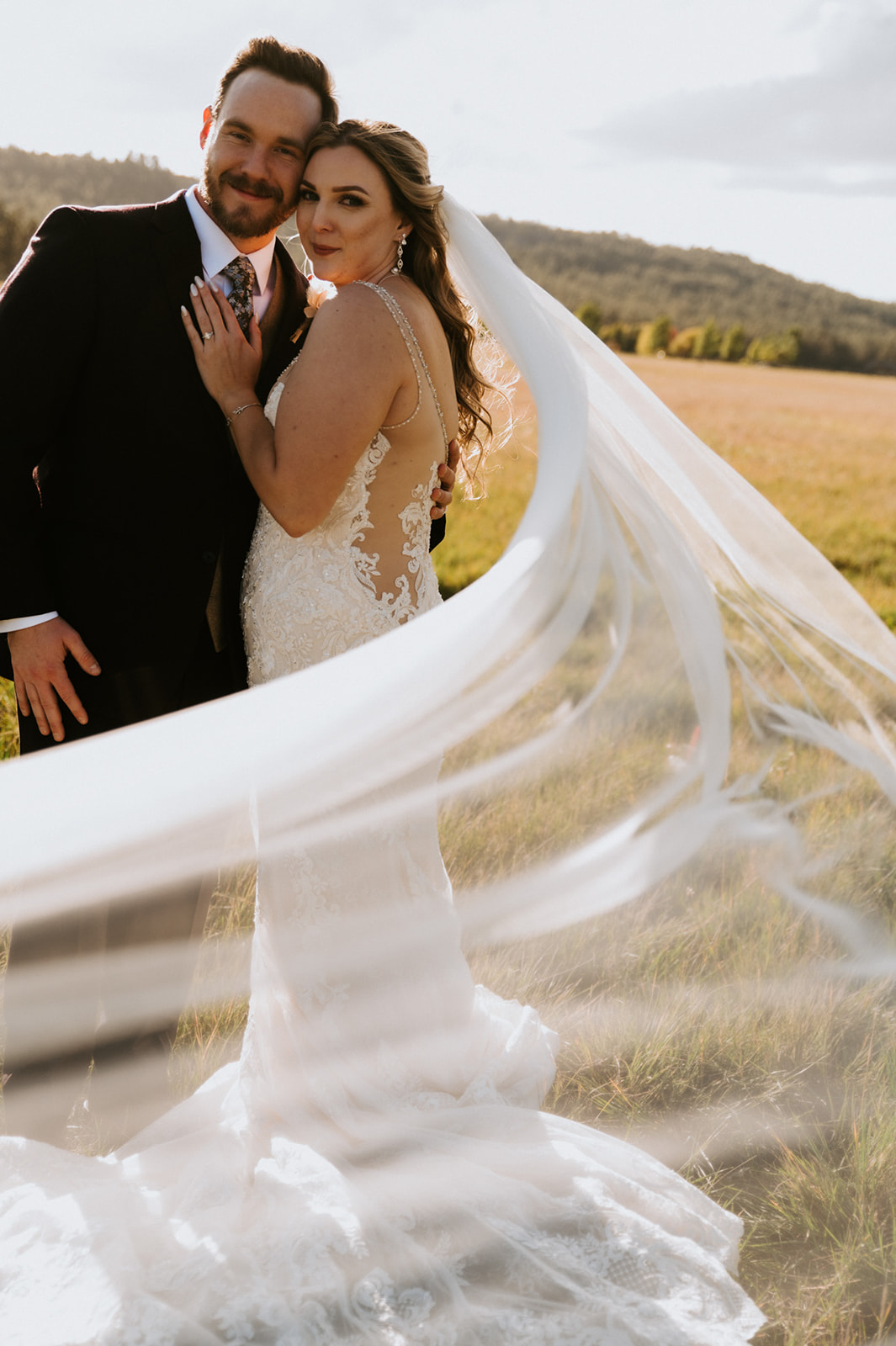 Newlyweds playfully pull away from their wedding party in a meadow, capturing the fun and connection that make planning an elopement so memorable.
