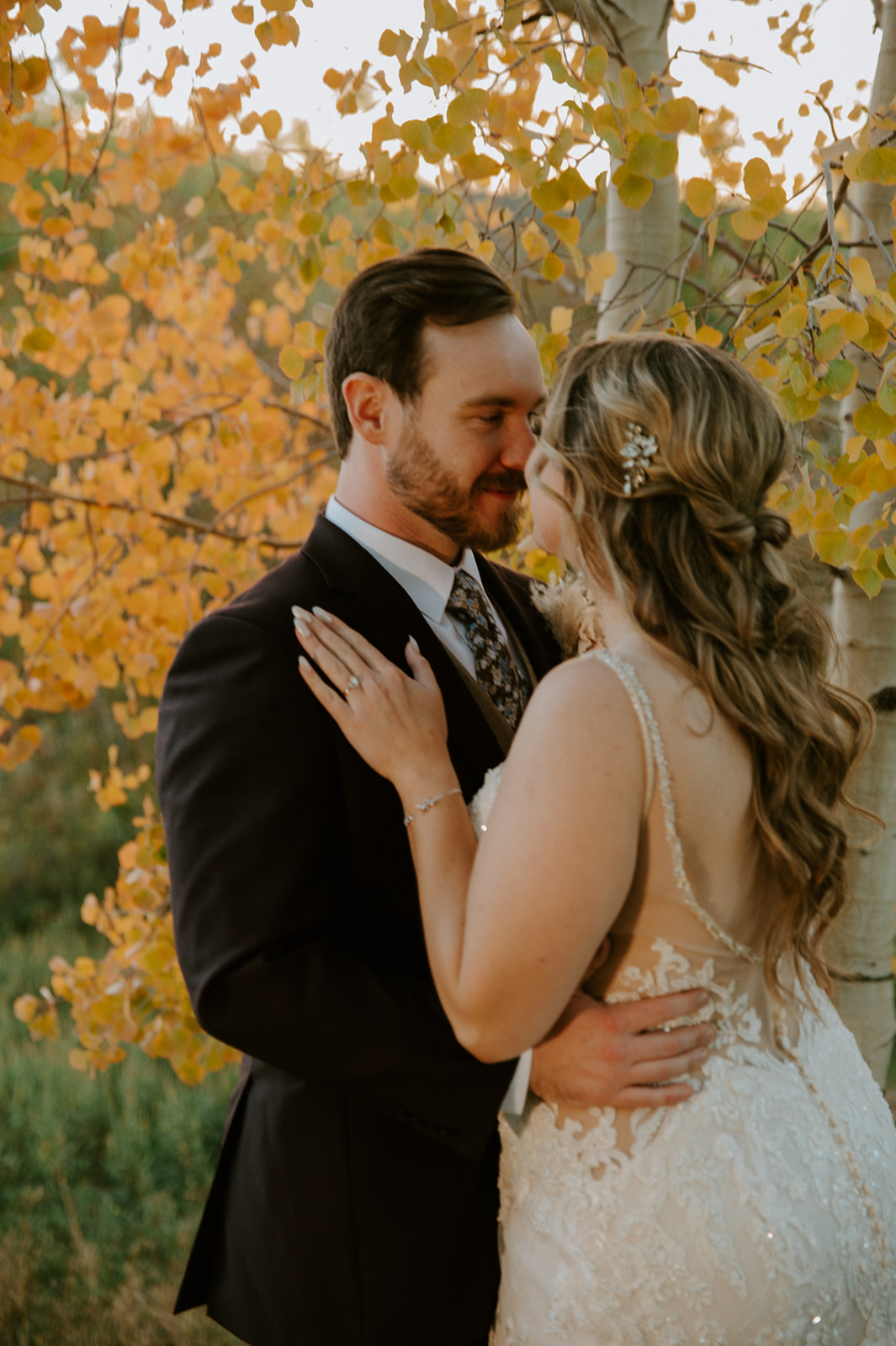 Romantic close-up portrait of the bride and groom beneath vibrant yellow aspen leaves.
