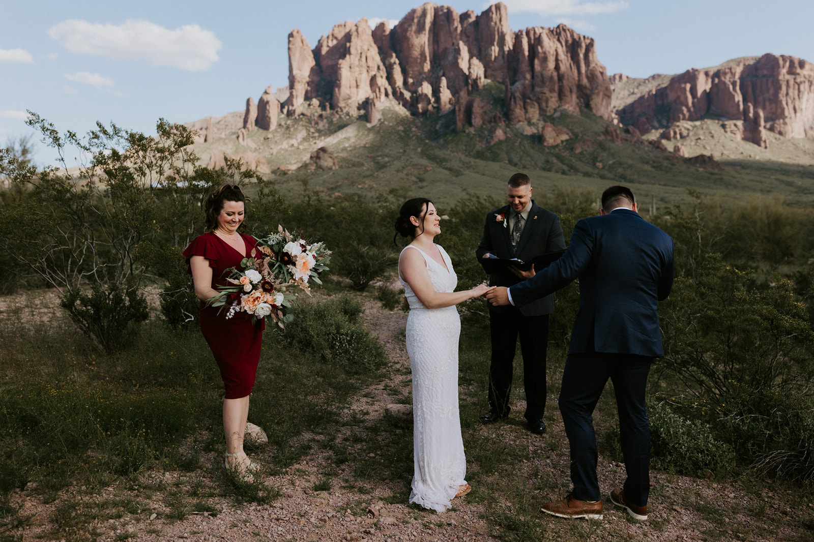 Intimate desert ceremony with officiant and family members gathered beneath the Superstition Mountains while eloping in Arizona.