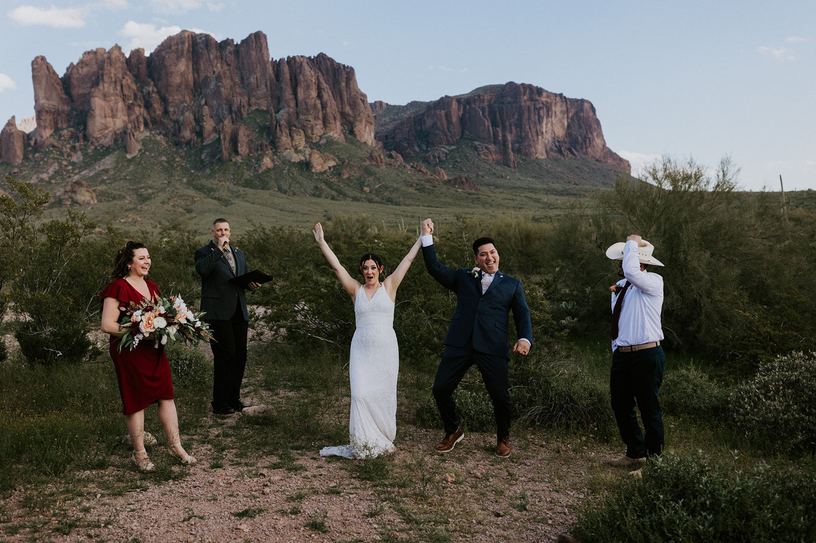 Newly married couple celebrating after their ceremony with mountain views and loved ones in the Arizona desert.