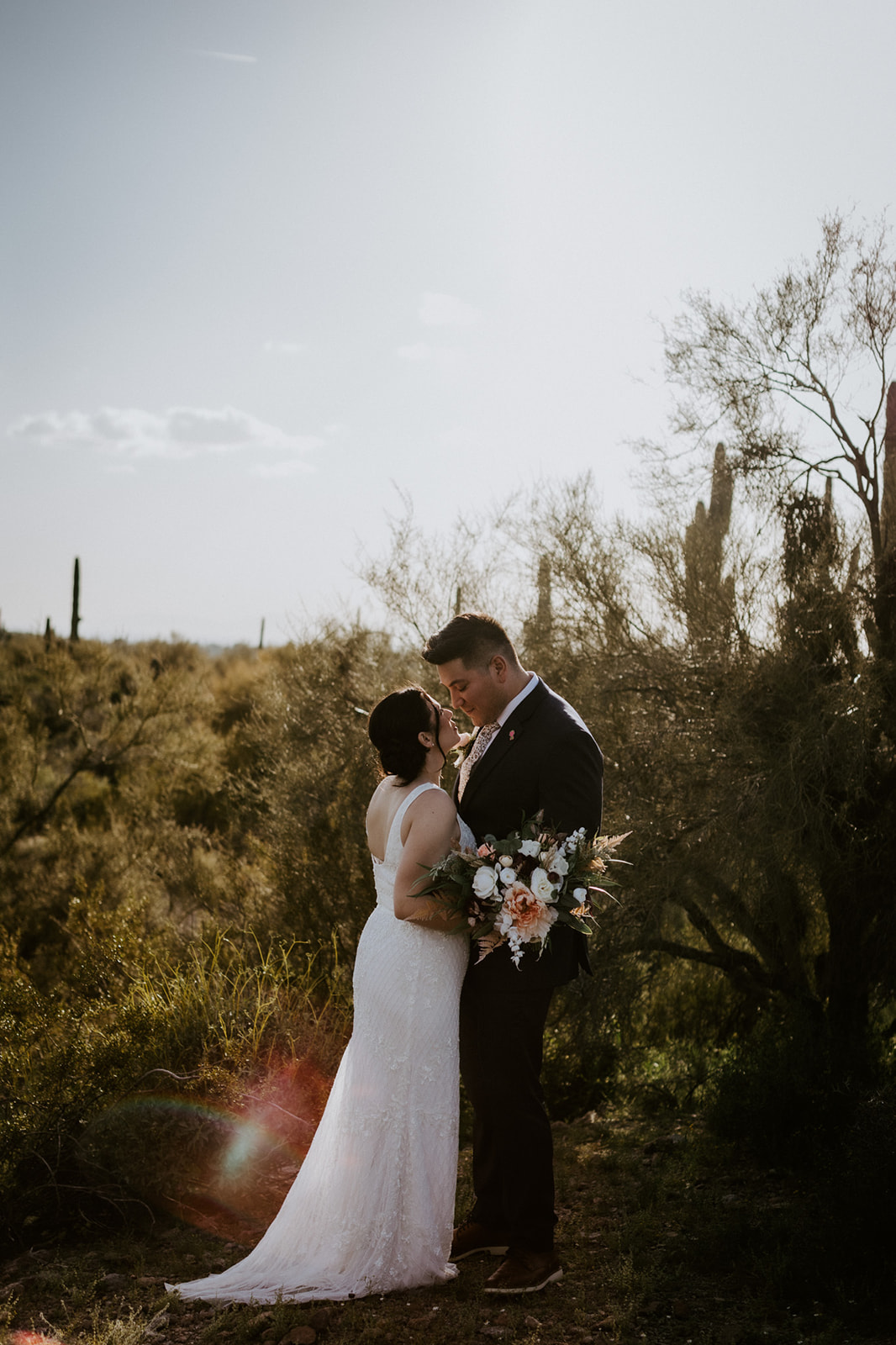 Intimate portrait of a couple embracing in the desert with wildflowers and a wedding bouquet
