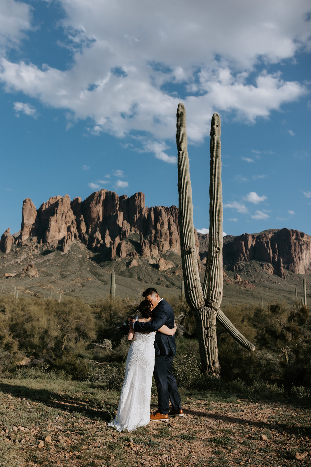 Bride and groom embracing beside a towering saguaro cactus during an intimate day eloping in Arizona
