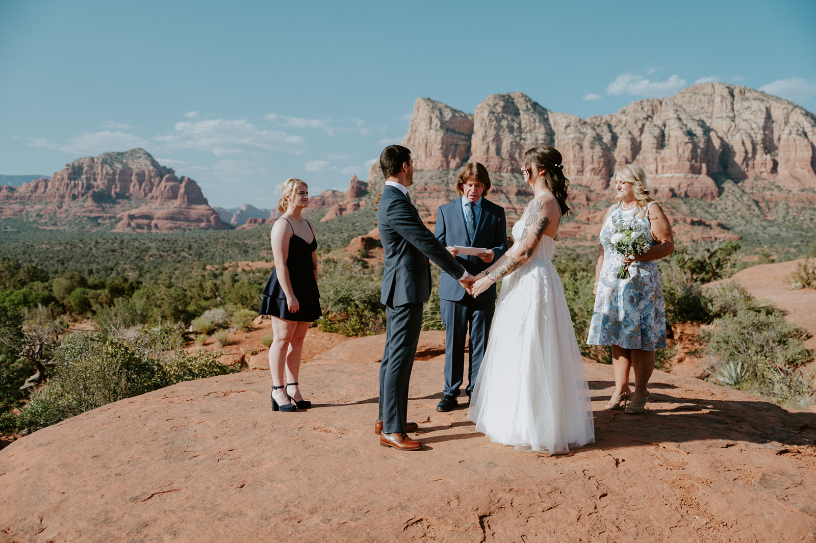 Small wedding ceremony with family members gathered on a red rock overlook while eloping in Arizona near Sedona.