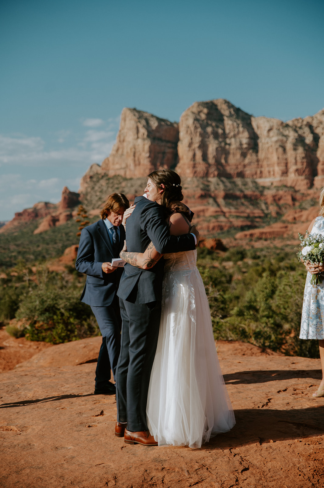 Emotional hug between newlyweds during a small Sedona ceremony surrounded by family and red rock views.