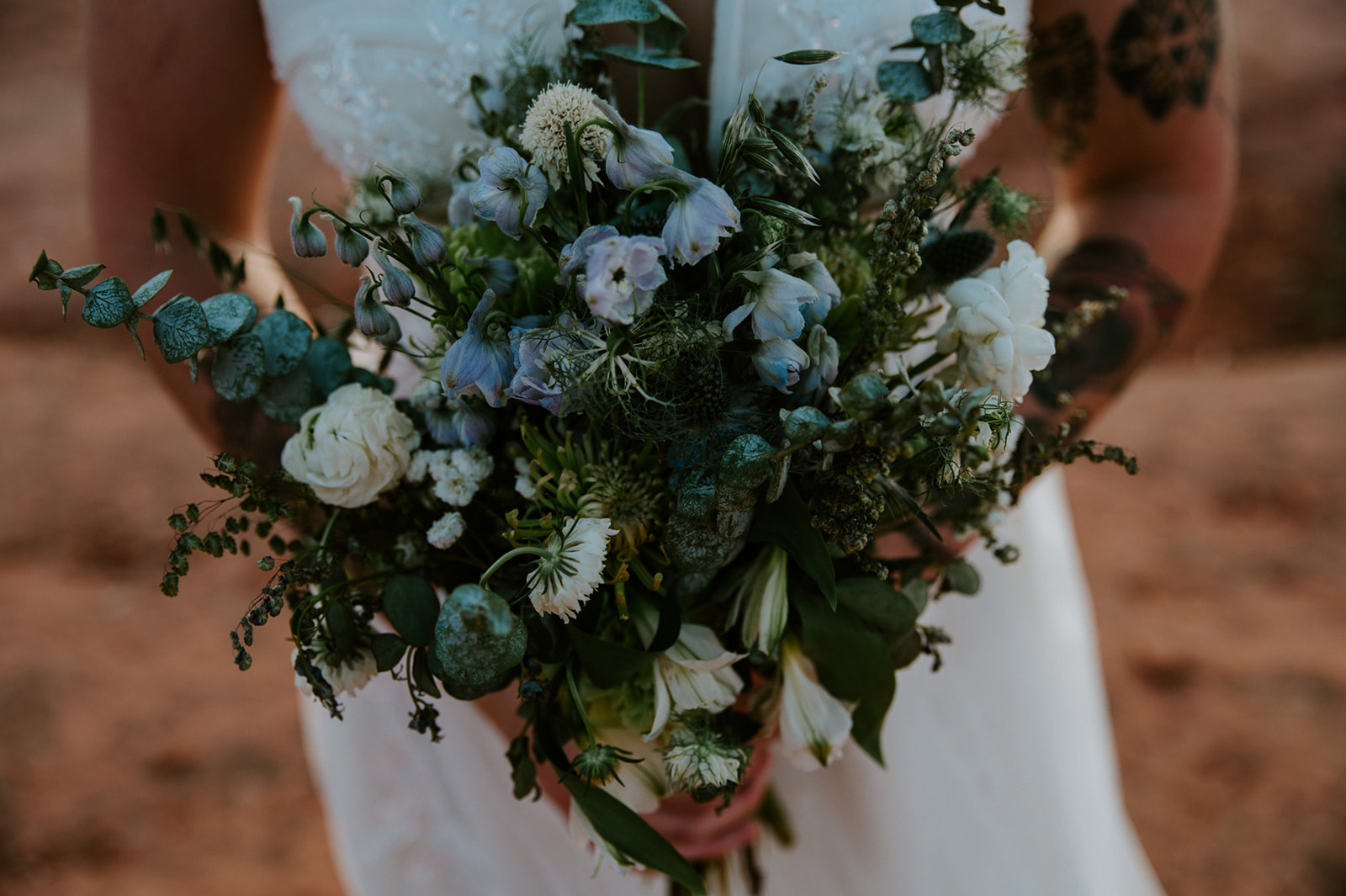 Organic wedding bouquet with white and blue florals held by a bride during her Sedona elopement.