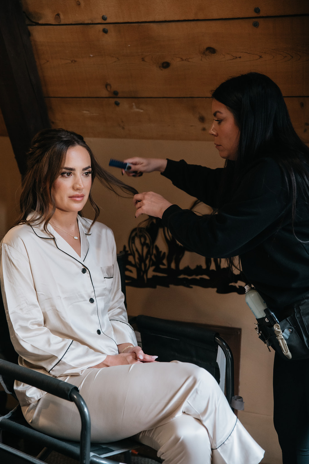 Bride getting her hair styled inside a cozy mountain cabin while getting ready for her wedding.