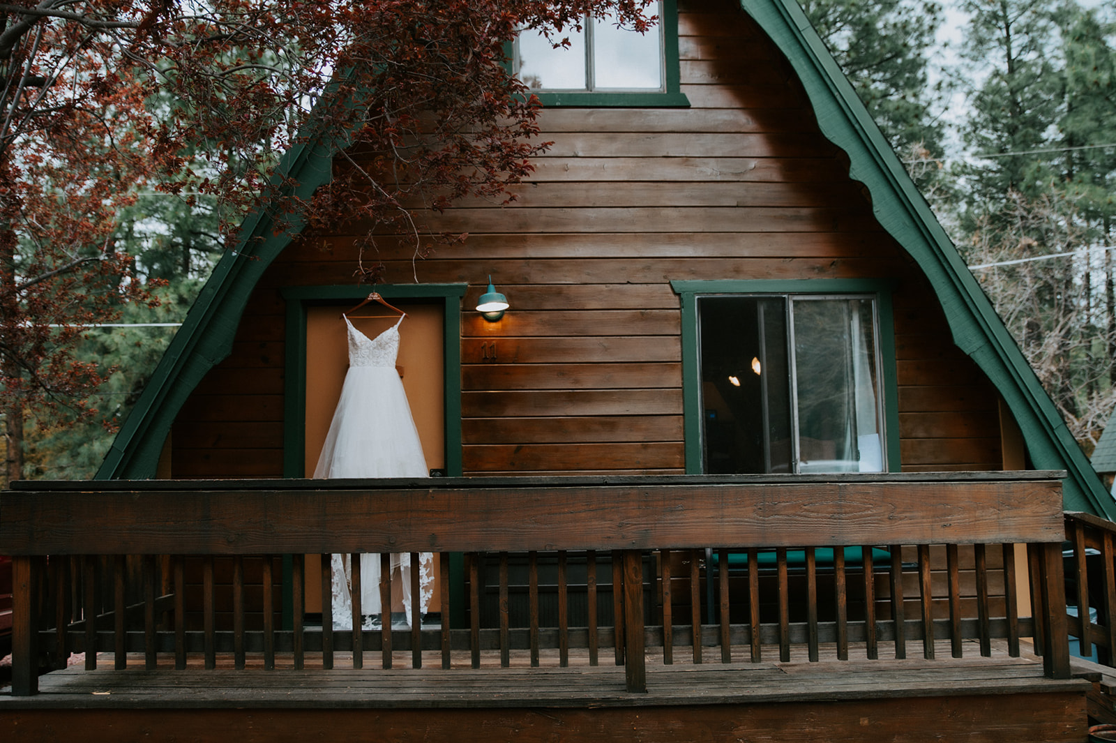 Wedding dress displayed outside a rustic A-frame cabin surrounded by pine trees at Cabins at Strawberry Hill.