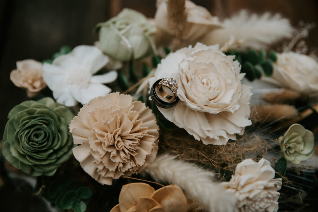 Wedding rings resting on ivory flowers and dried florals during a Cabins at Strawberry Hill wedding in Arizona.