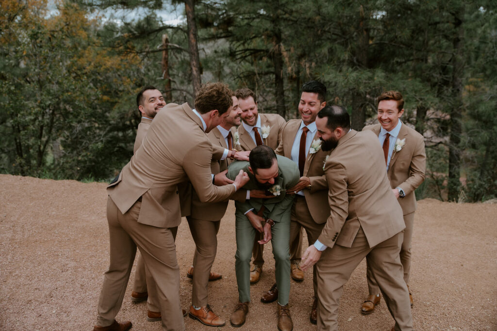 Groomsmen laughing together before the ceremony in the pine forest surrounding Cabins at Strawberry Hill.