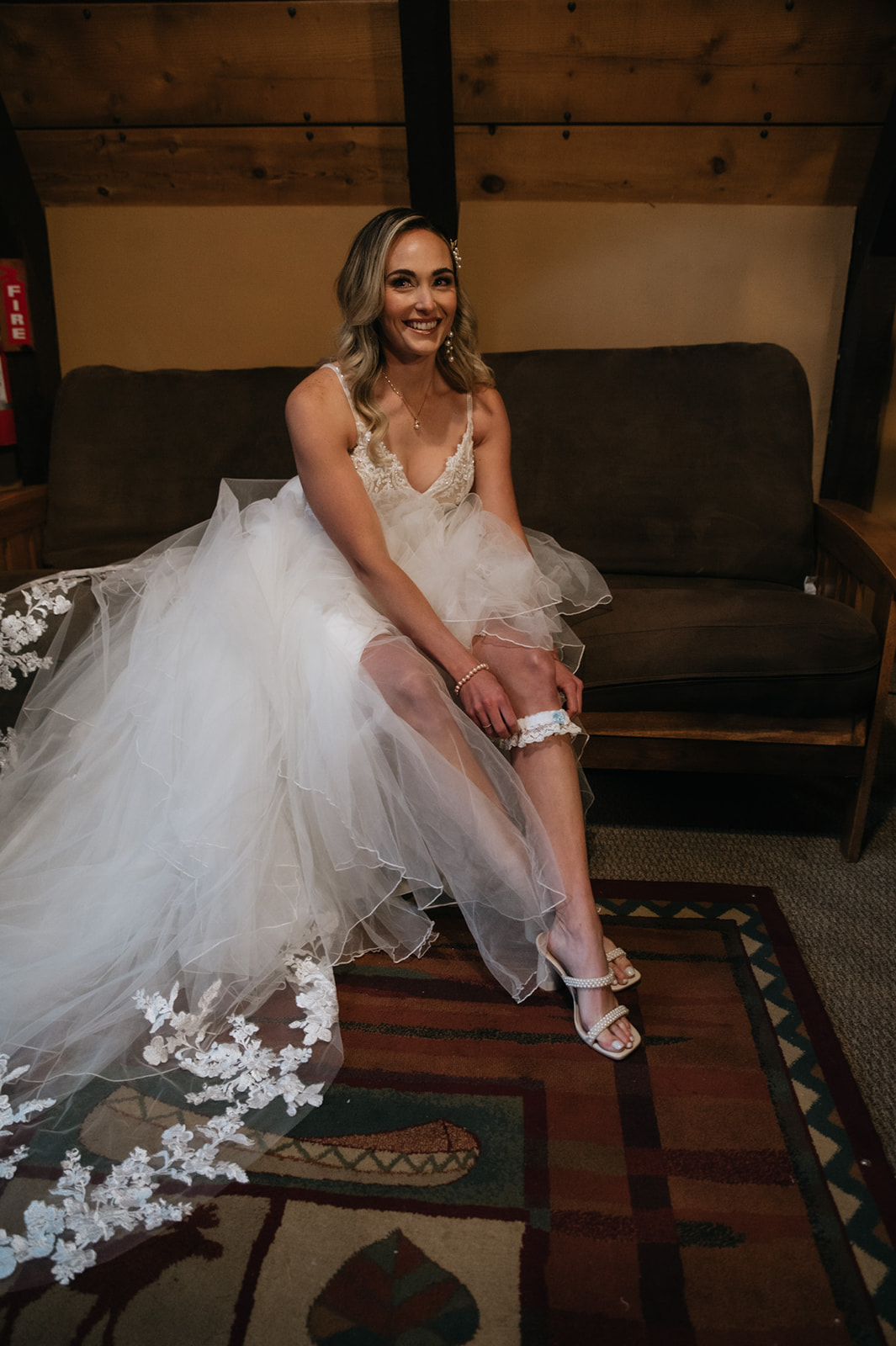 Bride sitting inside a cozy cabin while putting on her wedding garter before the ceremony.